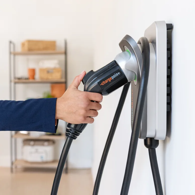 Hand docking the connector on a wall-mounted ChargePoint Home Flex indoors