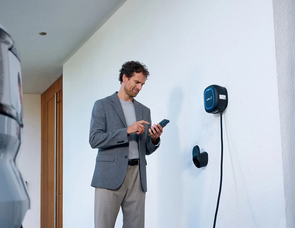Owner managing a wall-mounted Pulsar Plus from the myWallbox phone app